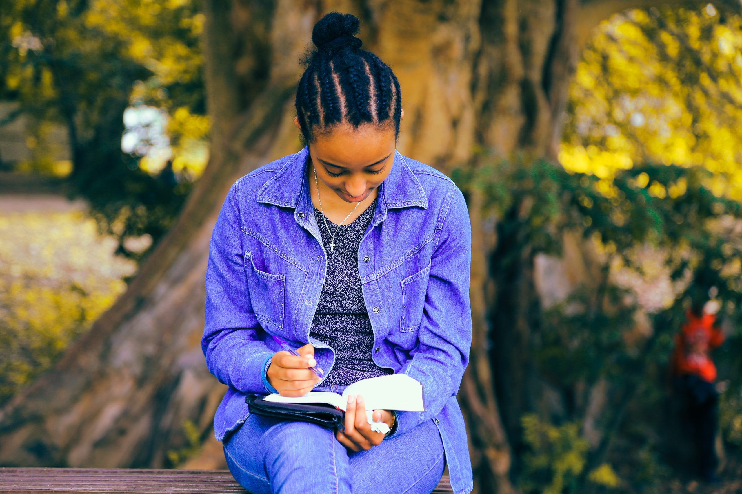 A Black woman sitting on a bench reading