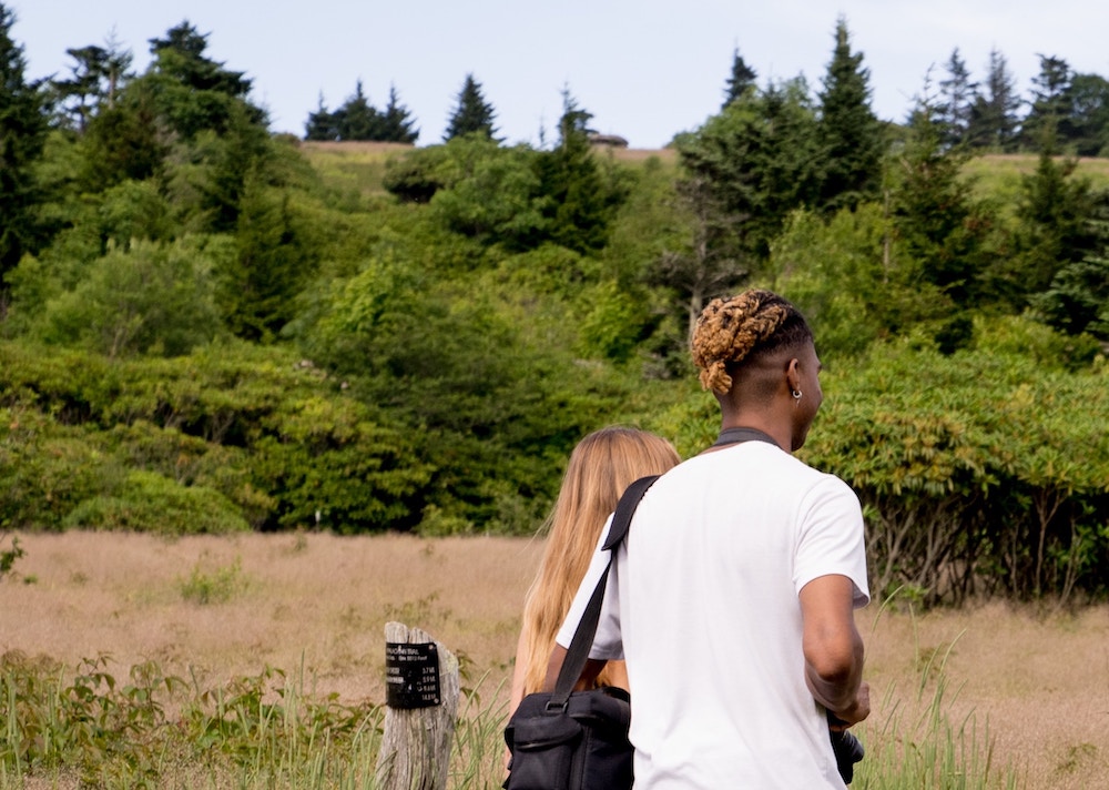 Two people walk into the woods.