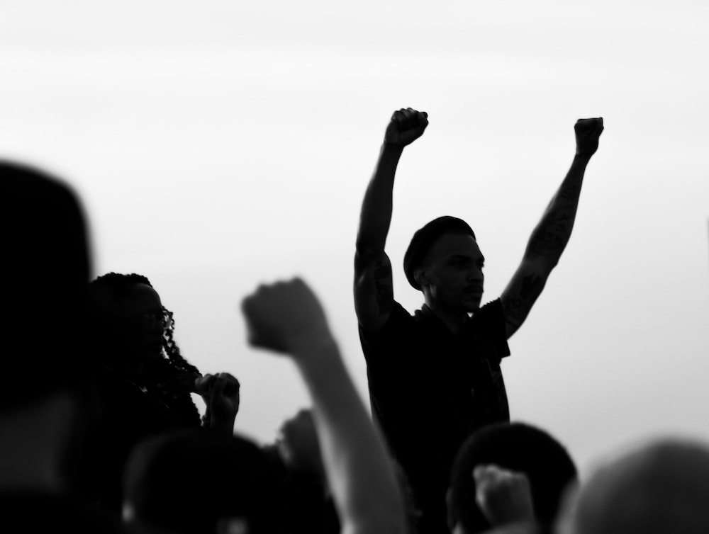 A man in silhouette raises two fists over his head